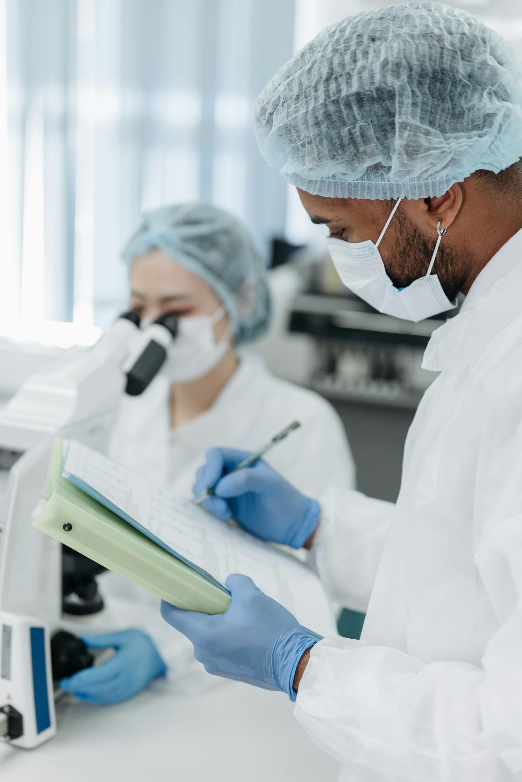 Scientists working in a modern lab with microscopes and notes.
